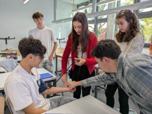 Mehrere Personen messen einem Jugendlichen den Blutdruck.