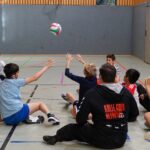 Schüler:innen spielen Sitzvolleyball