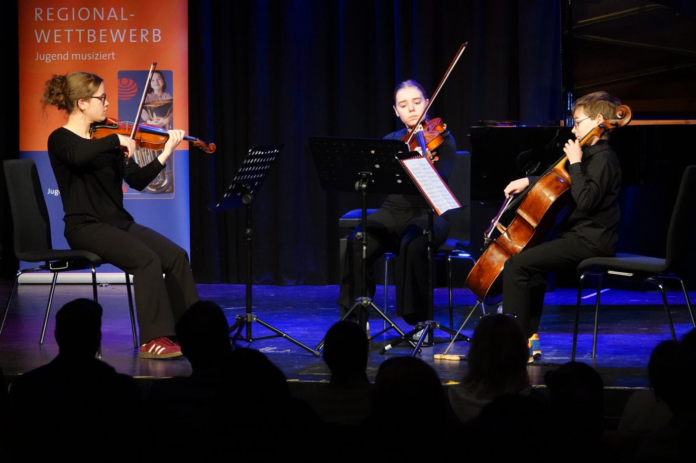 Drei Musiker spielen gemeinsam auf einer Bühne