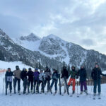 Skifahrer stehen in einer Reihe und heben ein Ski