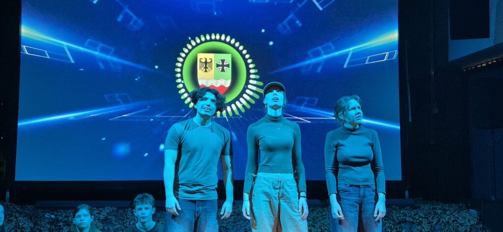 Drei Schauspieler gucken in die Ferne. 