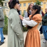 Ein Mädchen richtet die altertümliche Kleidung eines Jungen.