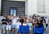 Sozialwissenschaftskurse der Q1 zu Gast in Brüssel Klassenstufe hält Europaflaggen vor Palamentshaus und lächelt